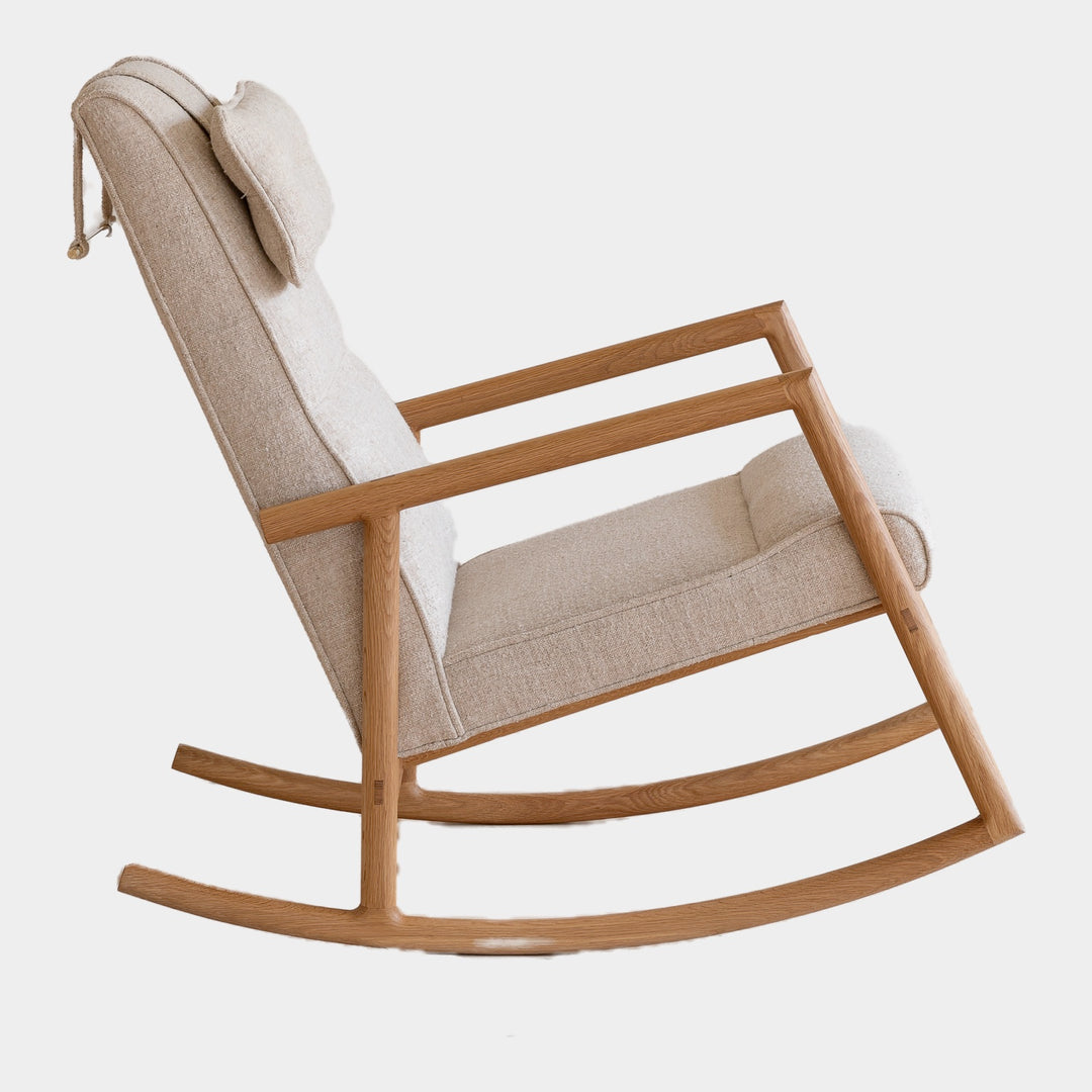 Side view of the MORESBY Rocker by Earl Home. This handmade wooden rocking chair features solid wood construction, black leather cushions, a custom upholstered seat, and an attached headrest.