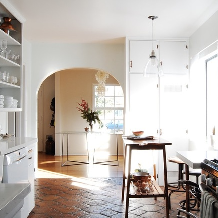 Modern kitchen with white cabinets, black stove, and wooden floor.