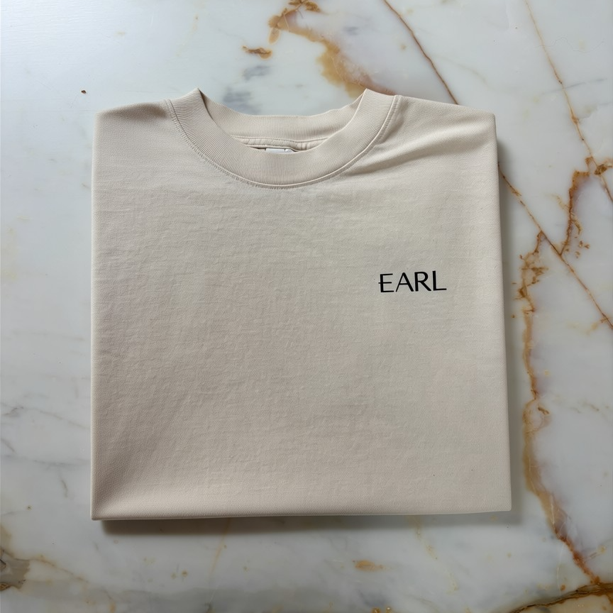 Beige Logo t-shirt with 'EARL' text on a marble surface