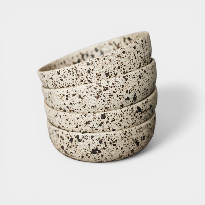 Stack of speckled ceramic bowls on a light background