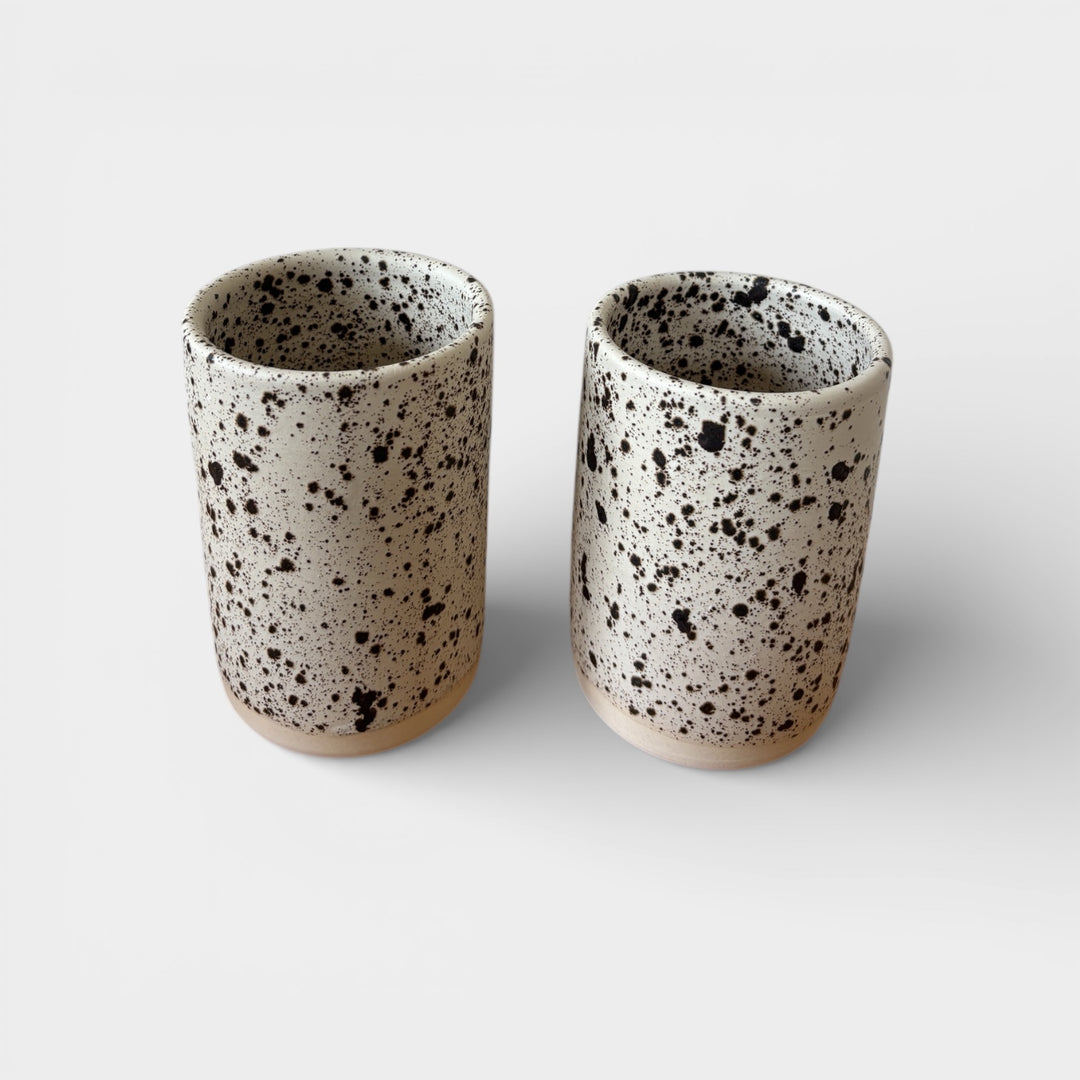 Two ceramic tumblers with a speckled pattern on a light background