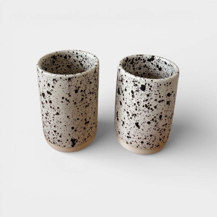 Two ceramic tumblers with a speckled pattern on a light background