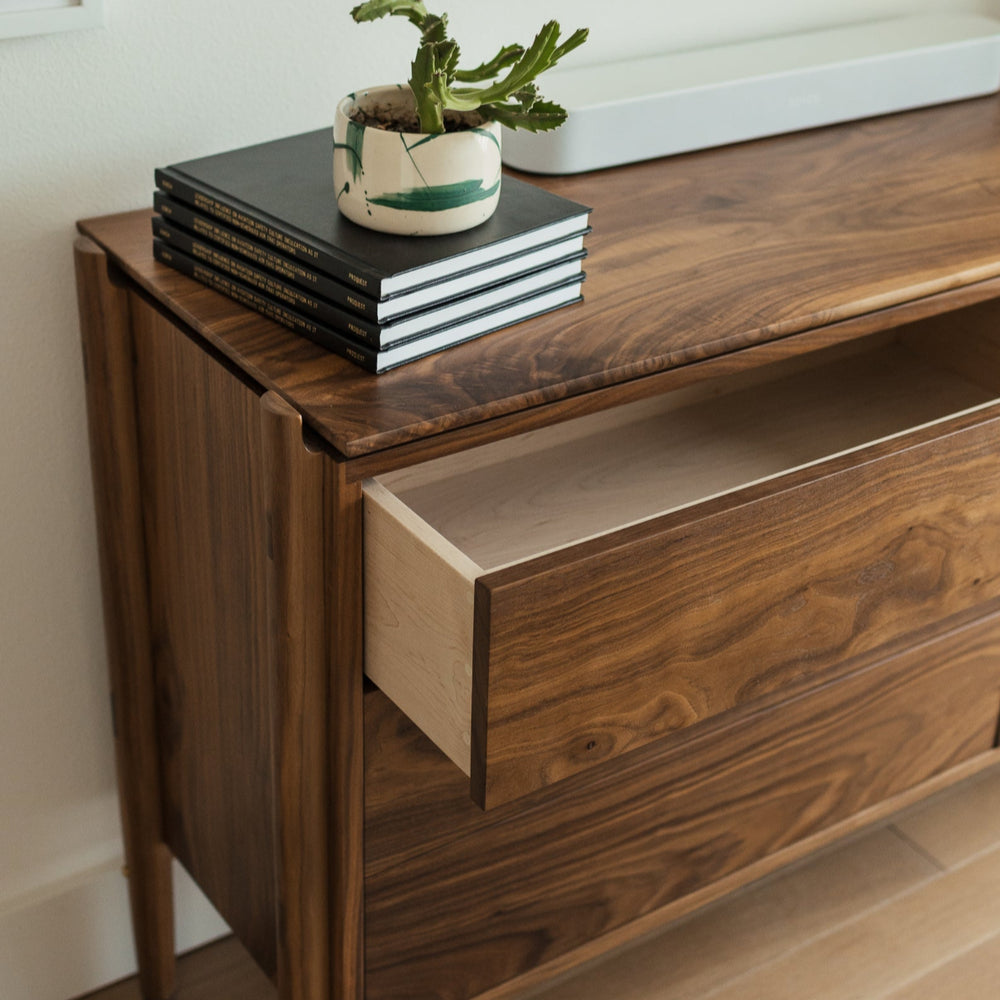 Timeless wooden walnut dresser with a floating top and solid wood construction with handcut joinery. Push to open and slow closing drawers. No hardware makes for a sleek and simple design. 