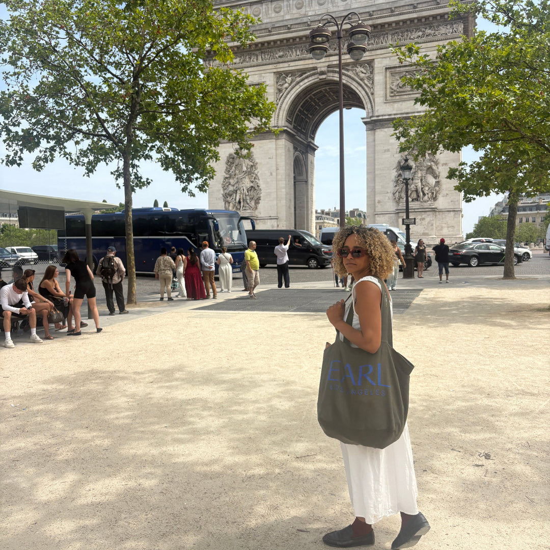 Amber Earl standing in front of the Arc de Triomphe in Paris holding XL EARL Tote