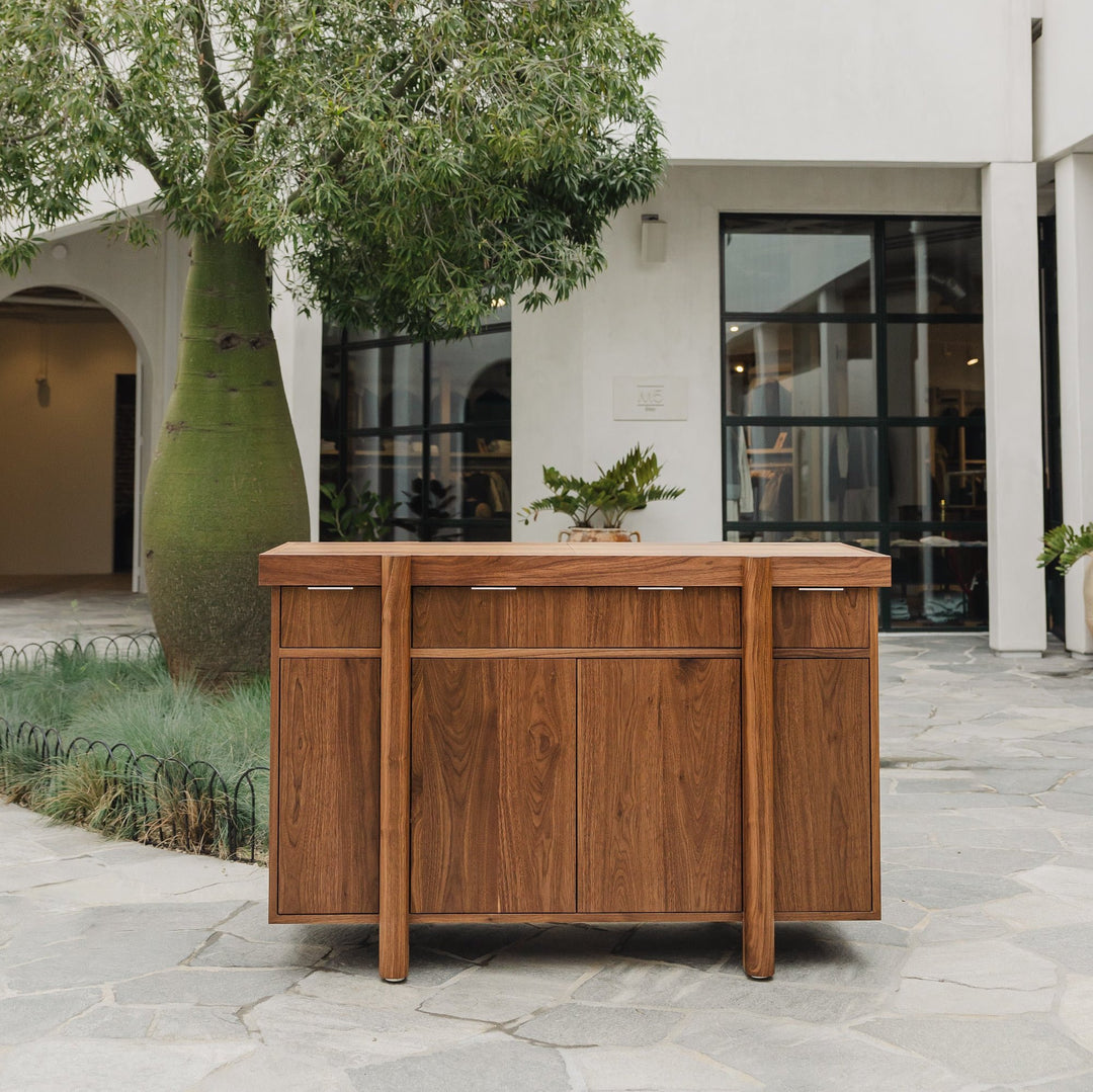 Handmade to order, the LAPILO Bar by Earl Home features open doors and drawers that reveal storage compartments and shelves, making it an ideal choice for a stylish and functional dry bar setup.