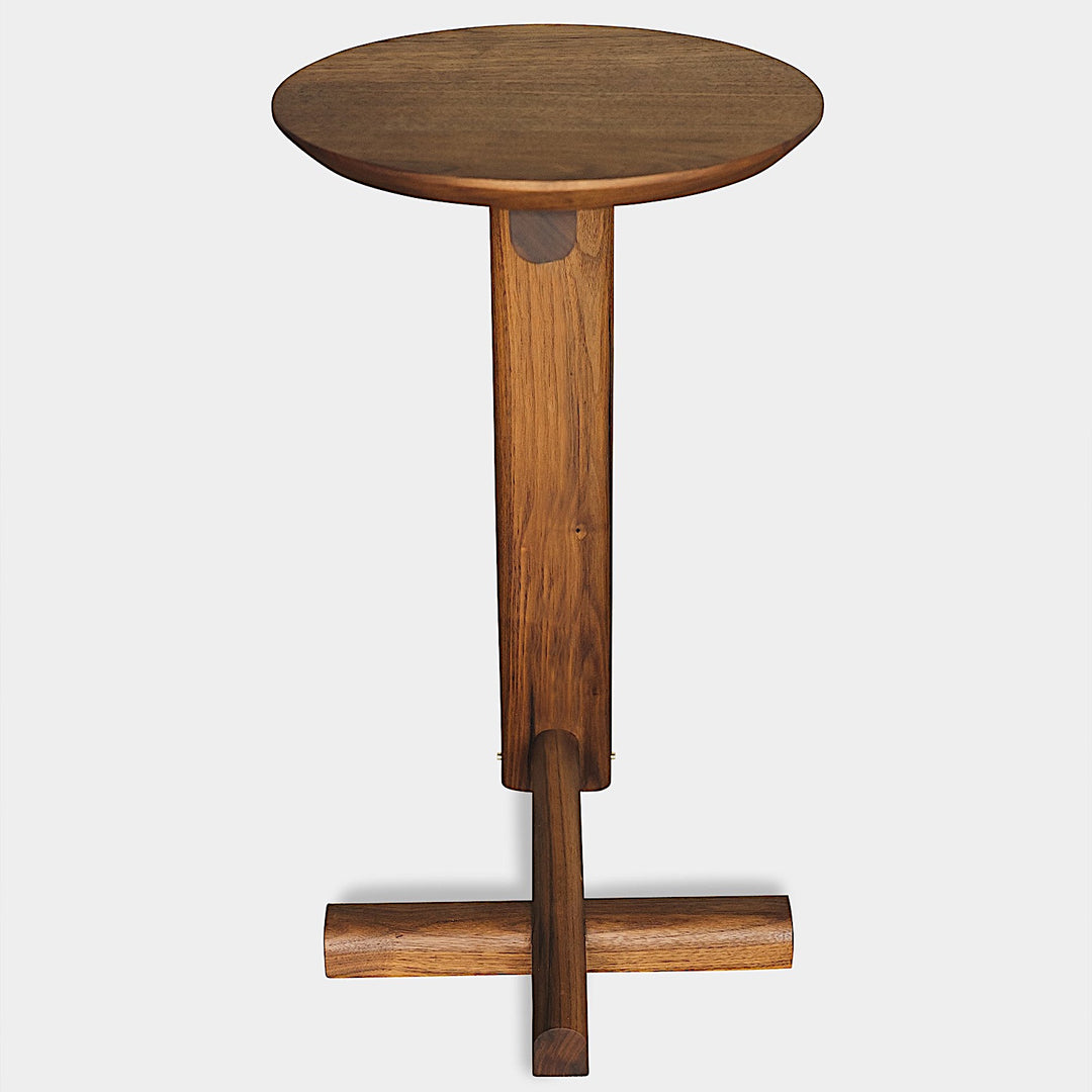 The MEDIA Side Table by Earl Home is a beautifully crafted piece featuring a solid wood construction with a round top and a custom-designed T-shaped base.