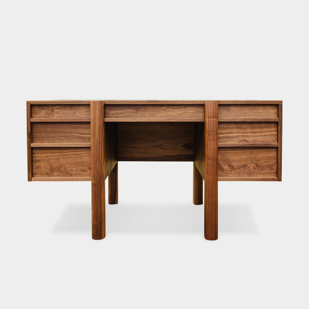 The LAPILO Desk by Earl Home is a handmade wooden piece with minimalist design, reminiscent of a classic tanker desk, featuring four side drawers and straight, sturdy legs.