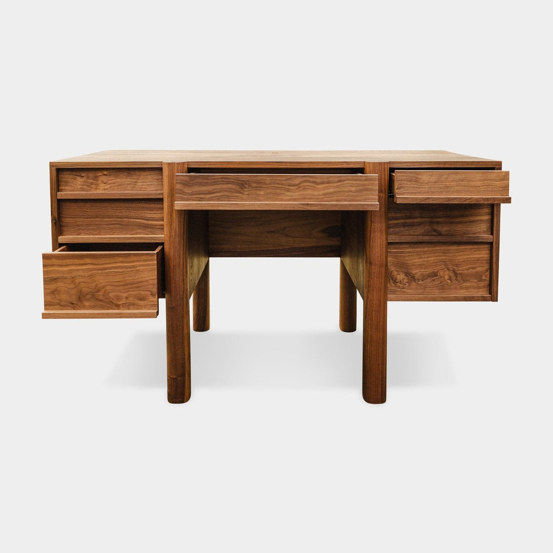 The LAPILO Desk by Earl Home is a handmade wooden piece with minimalist design, reminiscent of a classic tanker desk, featuring four side drawers and straight, sturdy legs.