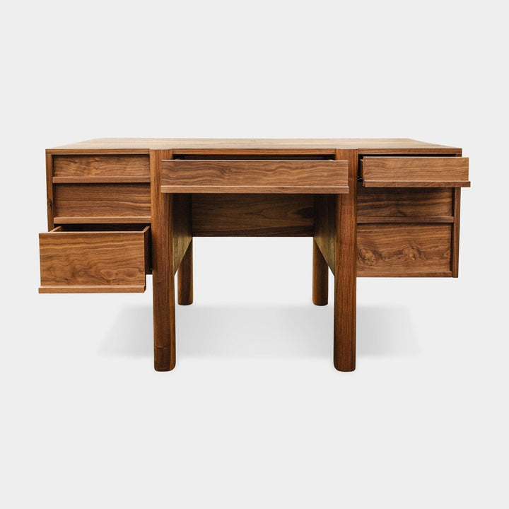 The LAPILO Desk by Earl Home is a handmade wooden piece with minimalist design, reminiscent of a classic tanker desk, featuring four side drawers and straight, sturdy legs.