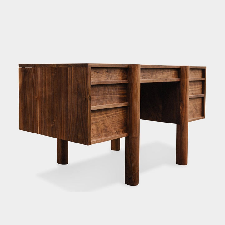 The LAPILO Desk by Earl Home is a handmade wooden piece with minimalist design, reminiscent of a classic tanker desk, featuring four side drawers and straight, sturdy legs.