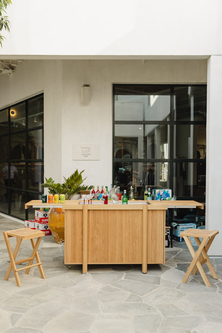 Handmade to order, the LAPILO Bar by Earl Home features open doors and drawers that reveal storage compartments and shelves, making it an ideal choice for a stylish and functional dry bar setup.