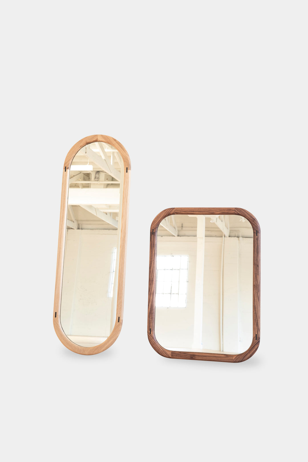 The HAROLD Mirror by Earl Home, a rectangular solid wood piece with metal inlay detailing, exquisitely reflects window light to enhance room brightness.