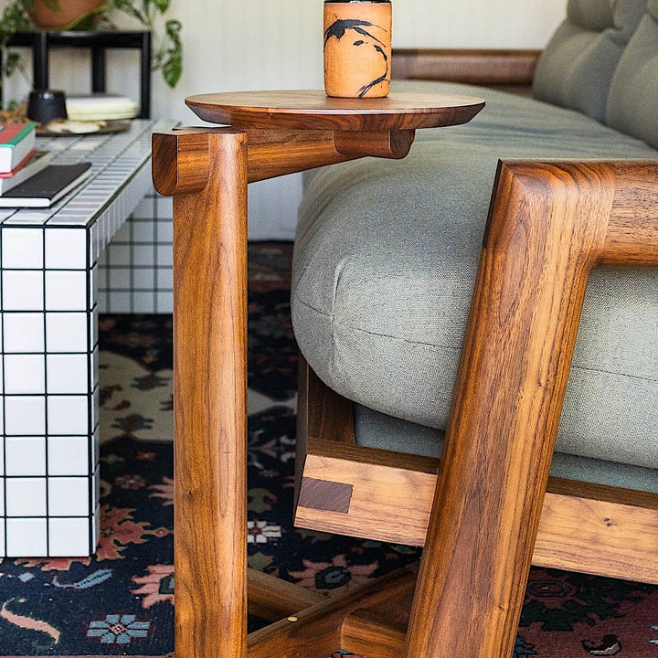 The MEDIA Side Table by Earl Home is a beautifully crafted piece featuring a solid wood construction with a round top and a custom-designed T-shaped base.