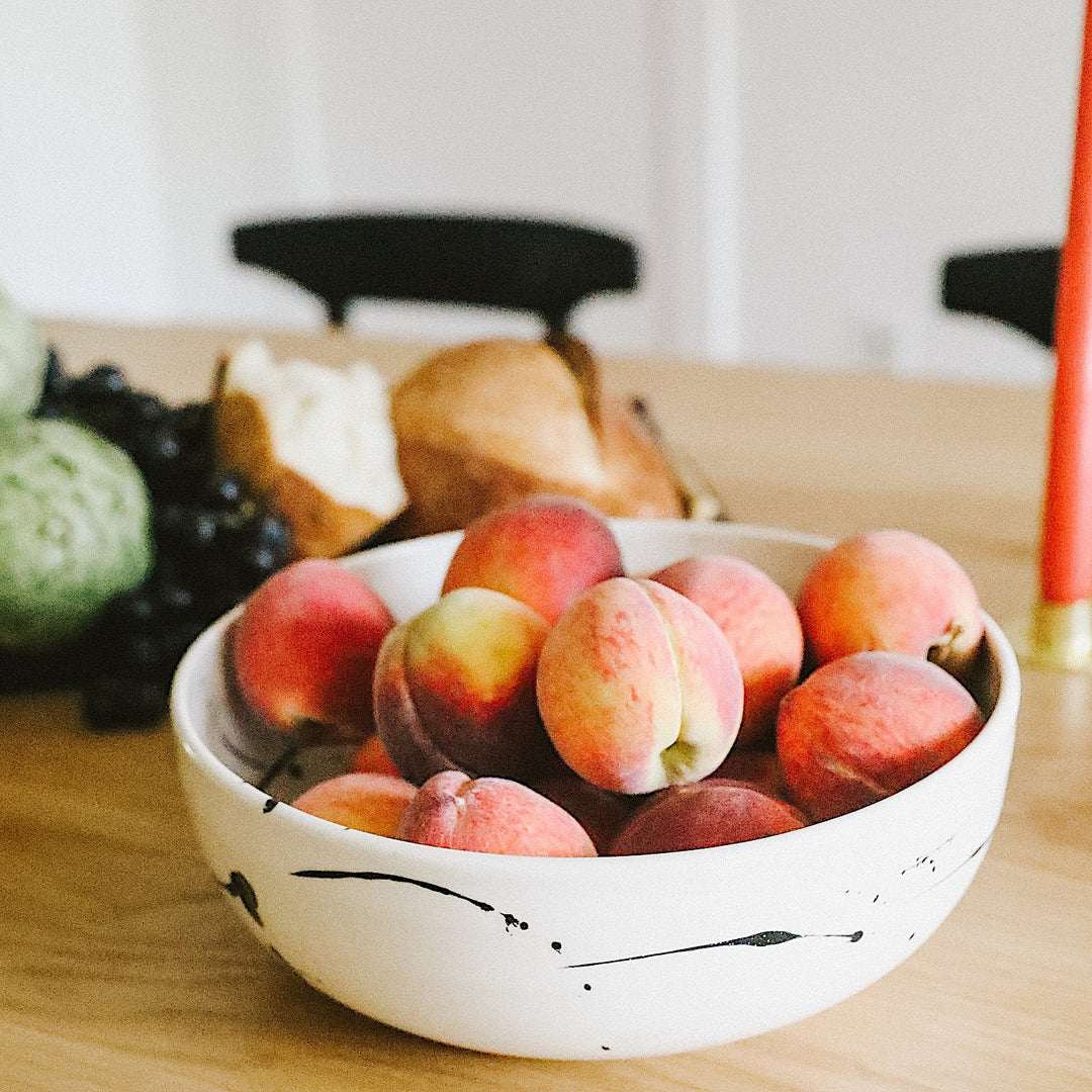 The Earl Home SERVING Bowl is a hand-thrown ceramic piece featuring a white interior and terracotta exterior with elegant swirl patterns. It is dishwasher and microwave safe.