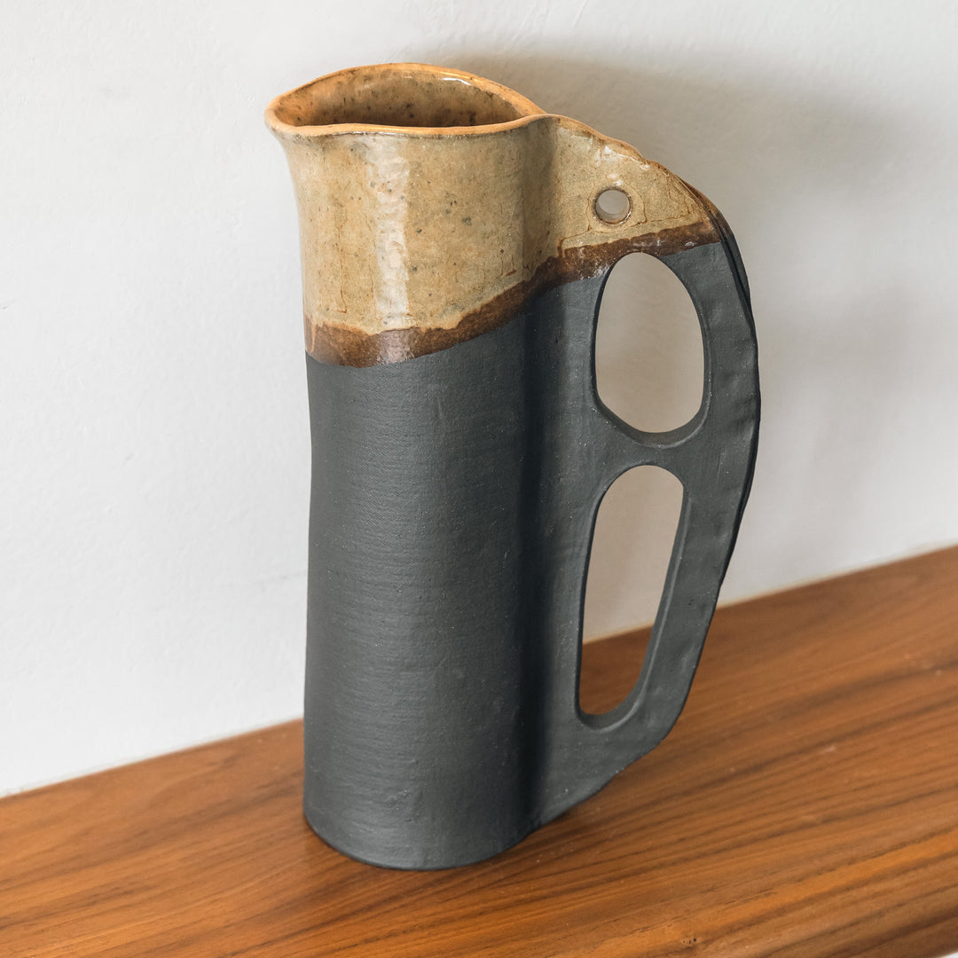 Round and slender pitcher in charcoal clay with a campfire glaze. Hand sculpted from slab rolled clay in Los Angeles, california. Made in America 