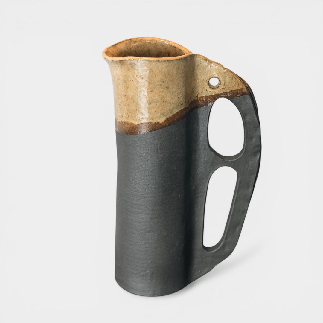 Round and slender pitcher in charcoal clay with a campfire glaze. Hand sculpted from slab rolled clay in Los Angeles, california. Made in America 