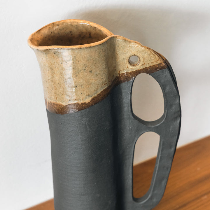 Round and slender pitcher in charcoal clay with a campfire glaze. Hand sculpted from slab rolled clay in Los Angeles, california. Made in America 