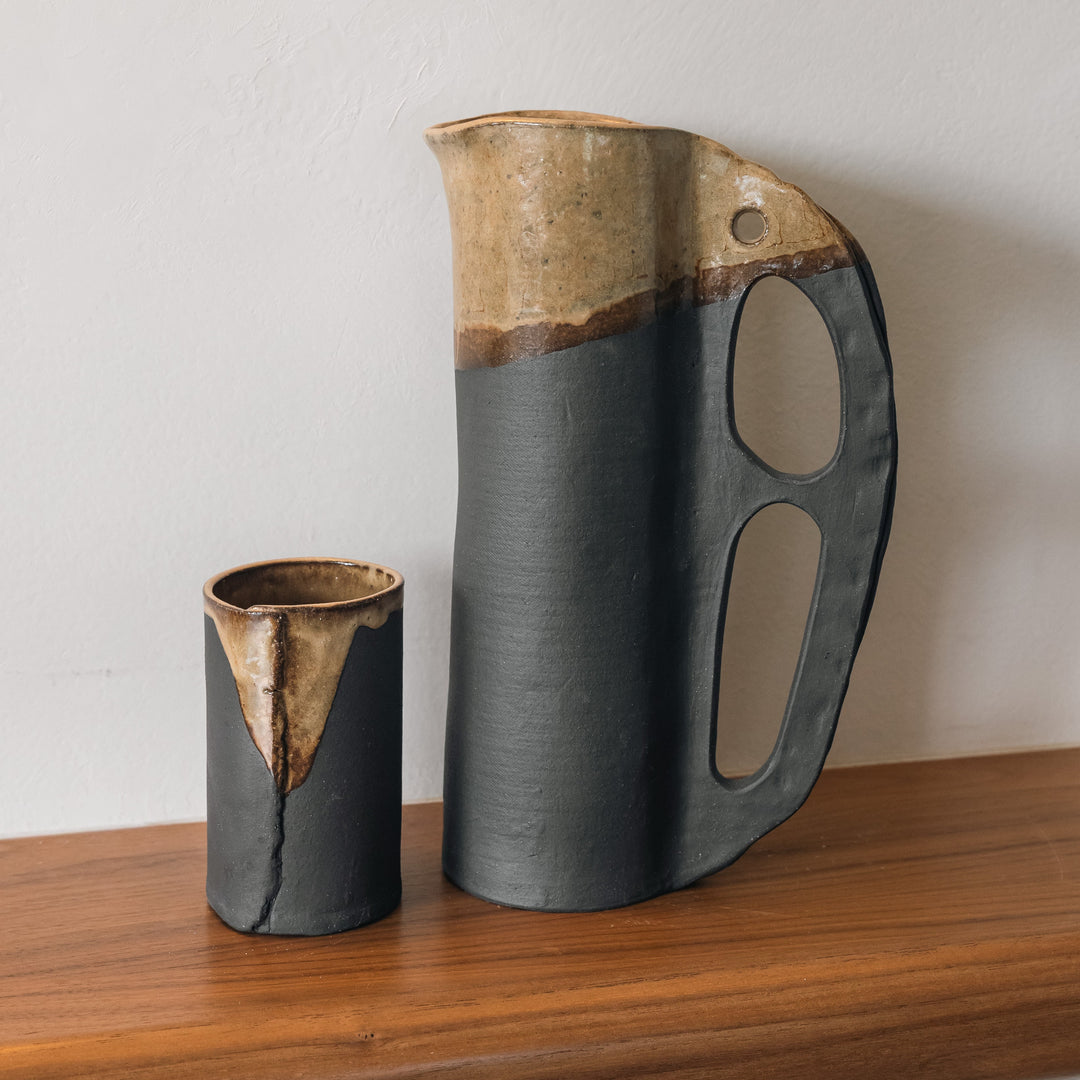 Round and slender pitcher in charcoal clay with a campfire glaze. Hand sculpted from slab rolled clay in Los Angeles, california. Made in America 
