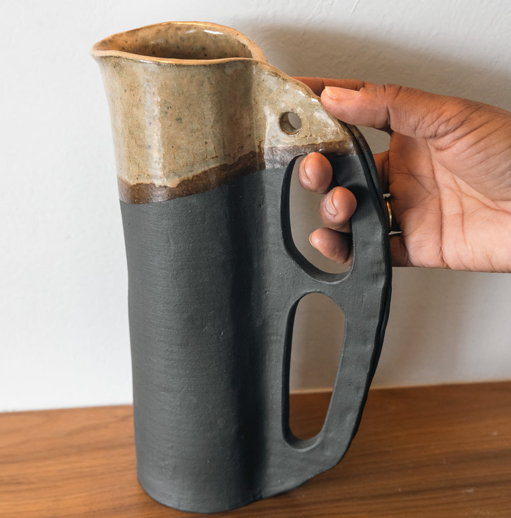 Round and slender pitcher in charcoal clay with a campfire glaze. Hand sculpted from slab rolled clay in Los Angeles, california. Made in America 