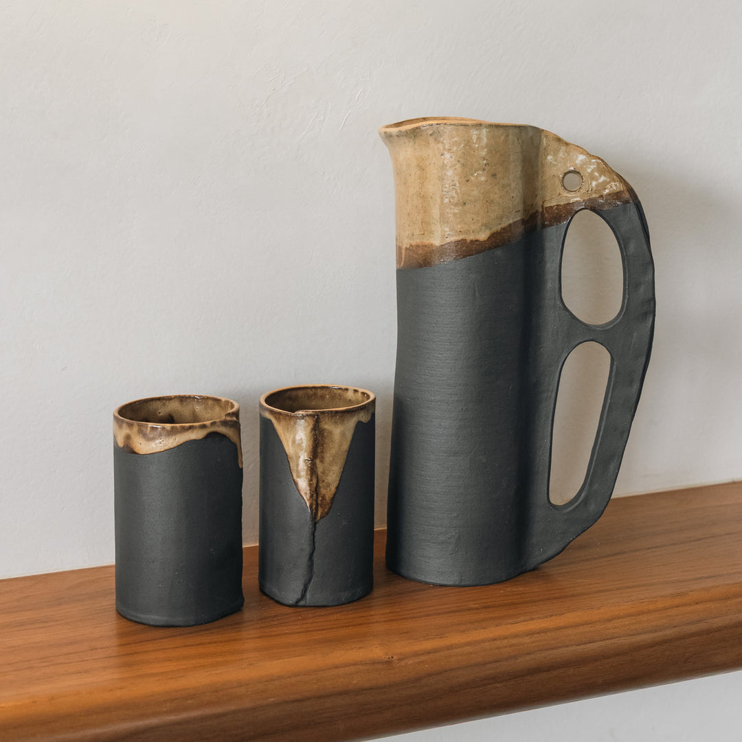 Round and slender pitcher in charcoal clay with a campfire glaze. Hand sculpted from slab rolled clay in Los Angeles, california. Made in America 