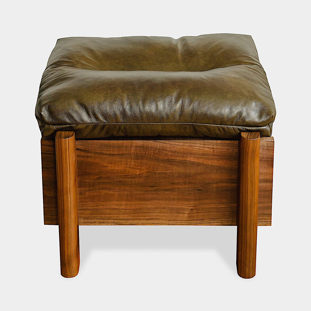 The TAMBU Ottoman by Earl Home is a stylish, handmade piece featuring a green cushioned top and offers storage seating against a white background.