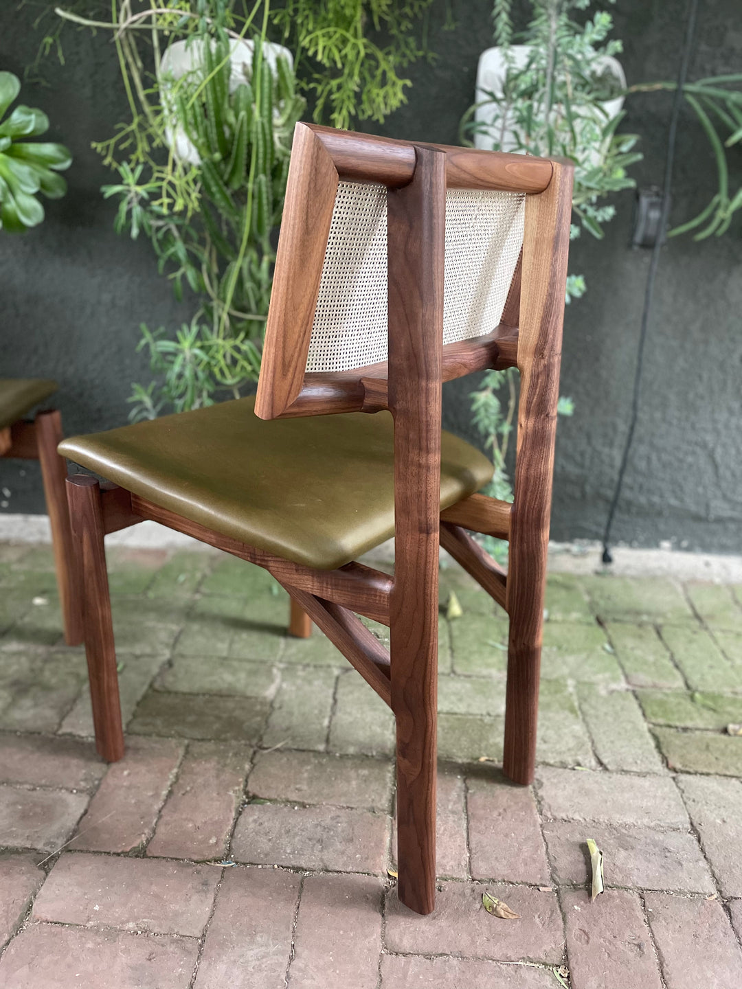 The KUNAI Dining Chair by Earl Home is handcrafted to order, featuring a solid wood frame, brown leather seat, and woven backrest.