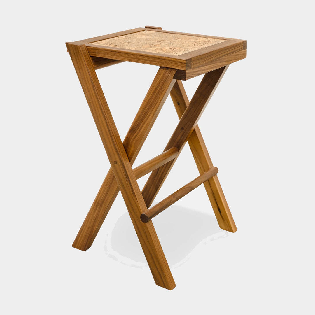 The LAPILO Folding Stool by Earl Home features an angular solid wood frame with a marbled cork seat and cross-legged design in a sleek finish.