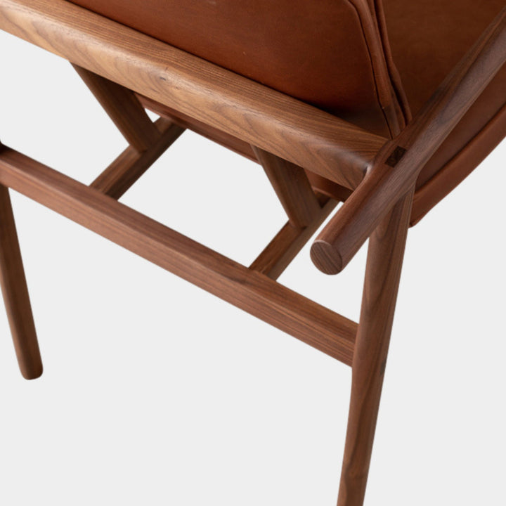 The MORESBY Captain Chair by Earl Home is hand-made with a custom upholstered camel leather seat that is a rich brown leather and walnut solid wood, set against a white background.