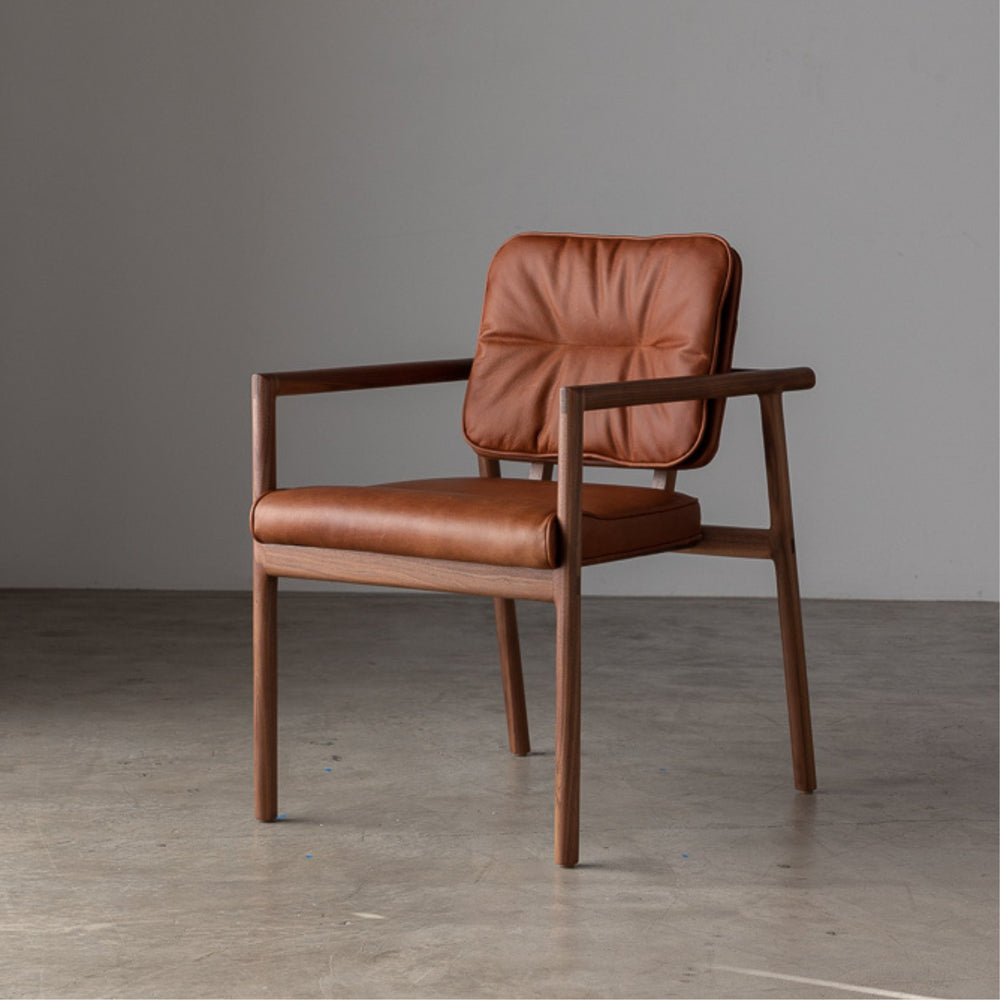 The MORESBY Captain Chair by Earl Home is hand-made with a custom upholstered camel leather seat that is a rich brown leather and walnut solid wood, set against a white background.