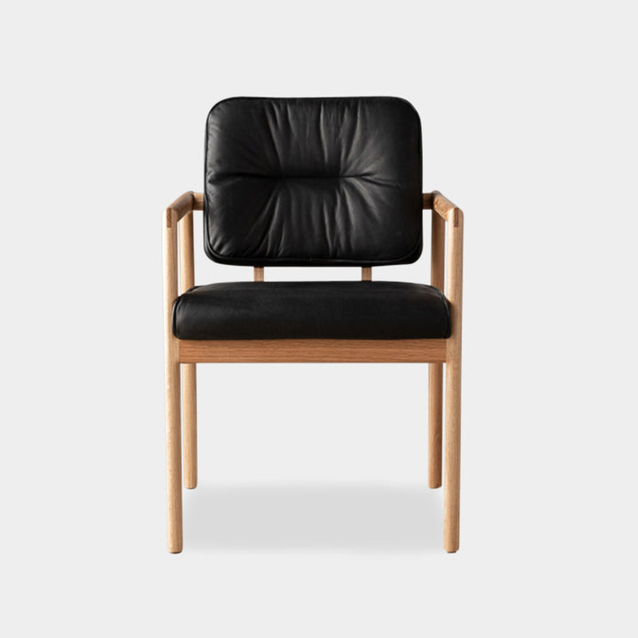 The MORESBY Captain Chair by Earl Home is hand-made with a custom upholstered black leather seat that is a rich black leather and white oak solid wood, set against a white background.