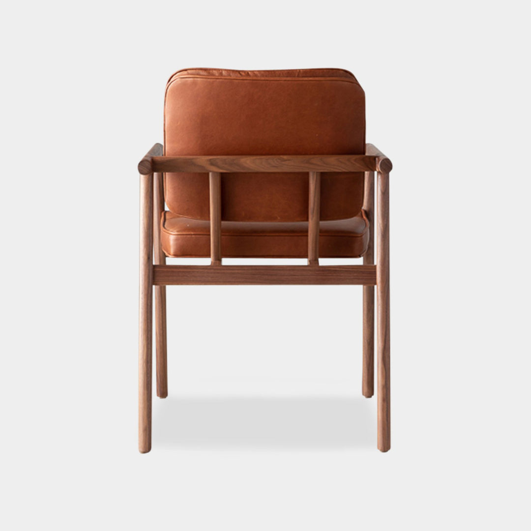 The MORESBY Captain Chair by Earl Home is hand-made with a custom upholstered camel leather seat that is a rich brown leather and walnut solid wood, set against a white background.