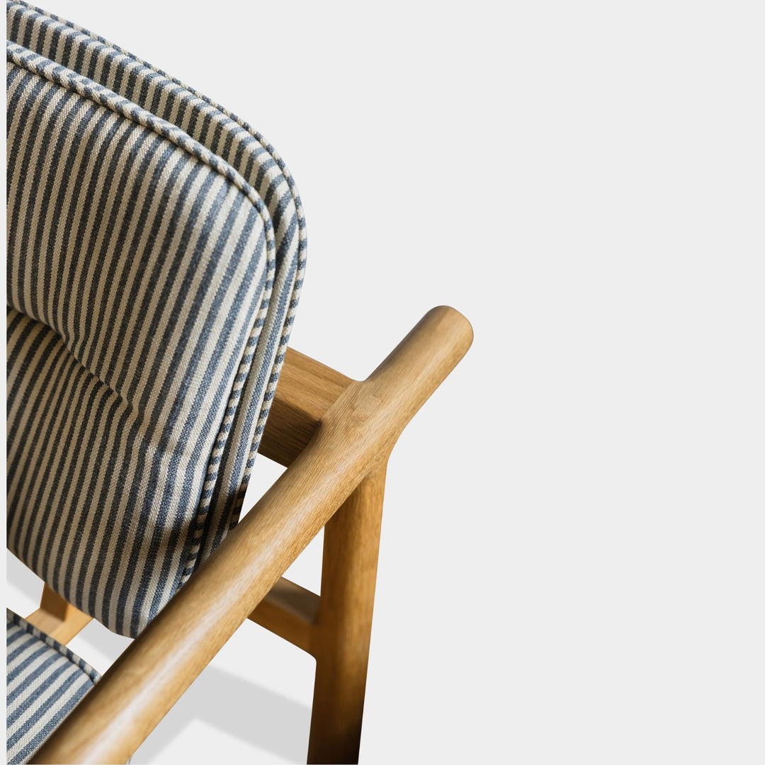 The MORESBY Lounge Chair by Earl Home is a modern, handmade piece featuring a sleek white oak frame and a custom upholstered perennials striped performance fabric cushion.