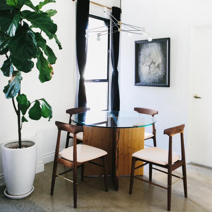 The Earl Home SABLE Dining Chair features a hand-made, bespoke charcoal fumed walnut wooden design with a curved backrest and four legs. Its flat seat exemplifies minimalist elegance, crafted from solid wood for lasting durability. Raw vegtan leather upholstery.