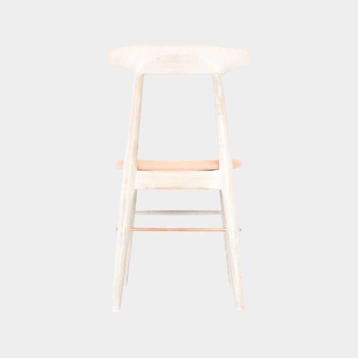 The Earl Home SABLE Dining Chair features a hand-made, bleached oak wooden design with a curved backrest and four legs. Its flat seat exemplifies minimalist elegance, crafted from solid wood for lasting durability. Raw vegtan leather upholstery.