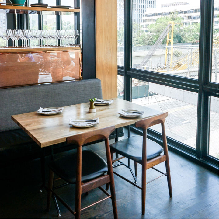 The Earl Home SABLE Dining Chair features a hand-made, walnut wooden design with a curved backrest and four legs. Its flat seat exemplifies minimalist elegance, crafted from solid wood for lasting durability. Black leather upholstery.