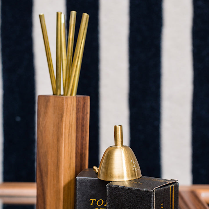 An elegant tall wooden vase with a two-tone walnut maple design graces the bar cart, displaying Earl Home's COCKTAIL Straws—thin golden rods that resemble brass.