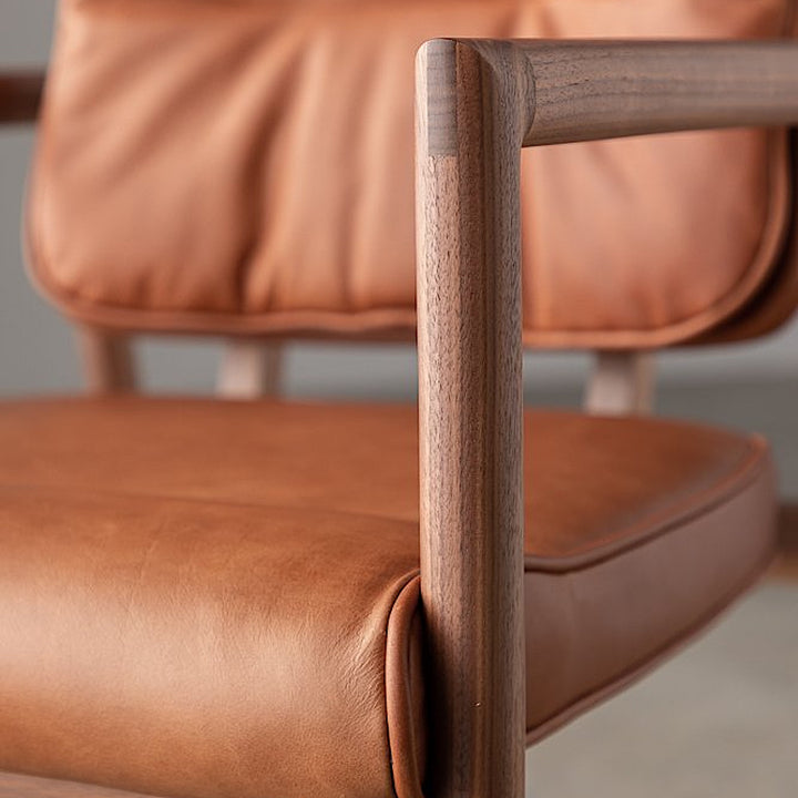 The MORESBY Captain Chair by Earl Home is hand-made with a custom upholstered seat in rich brown leather and solid wood, set against a white background.