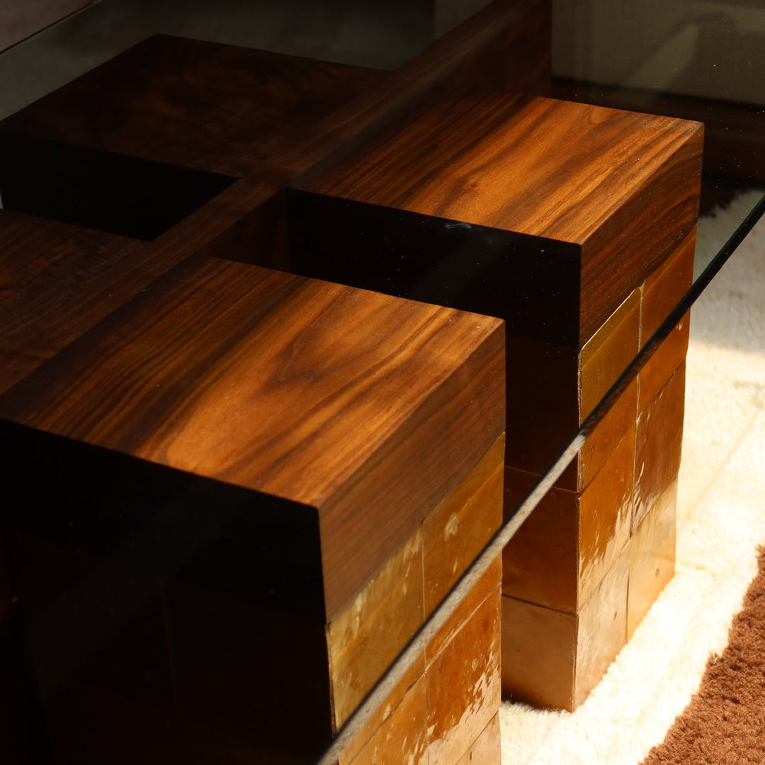 A close-up of a modern wooden furniture piece, likely a side table or stool, with a rich brown wood grain finish and glossy zellige tile, set on a patterned brown, white, and blue rug.