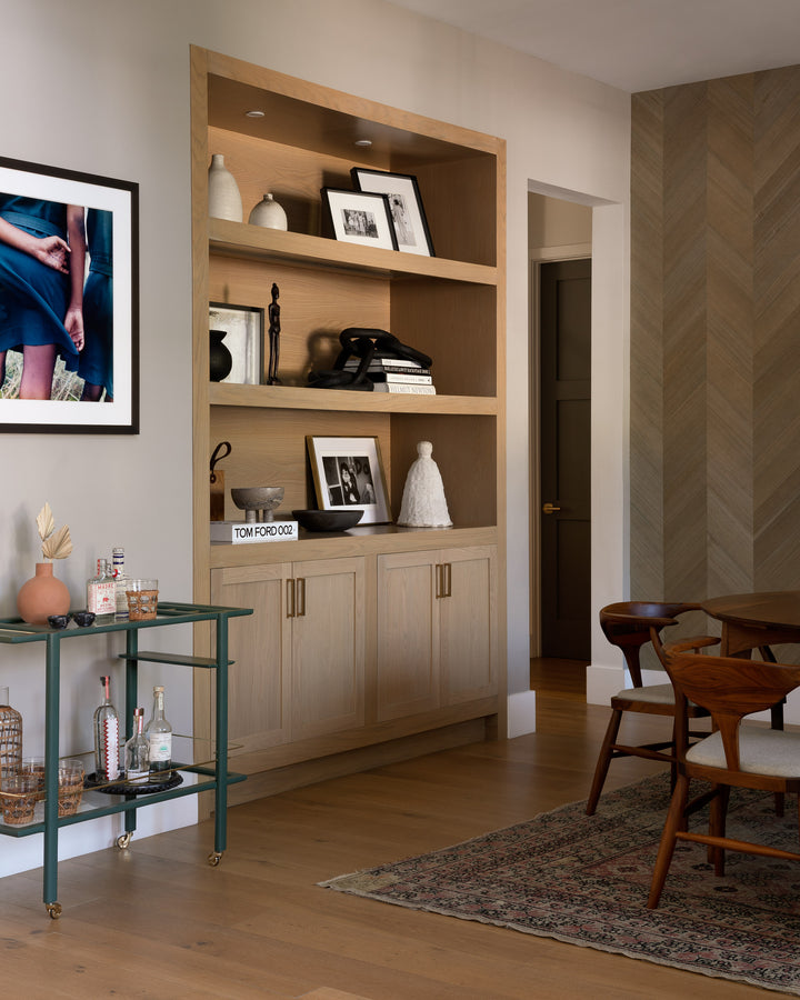 The BAR Cart from Earl Home is a solid wood bar cart on wheels with exquisite hand-cut joinery, featuring two shelves: a robust wood top and an elegant lower shelf made of tempered glass panels.